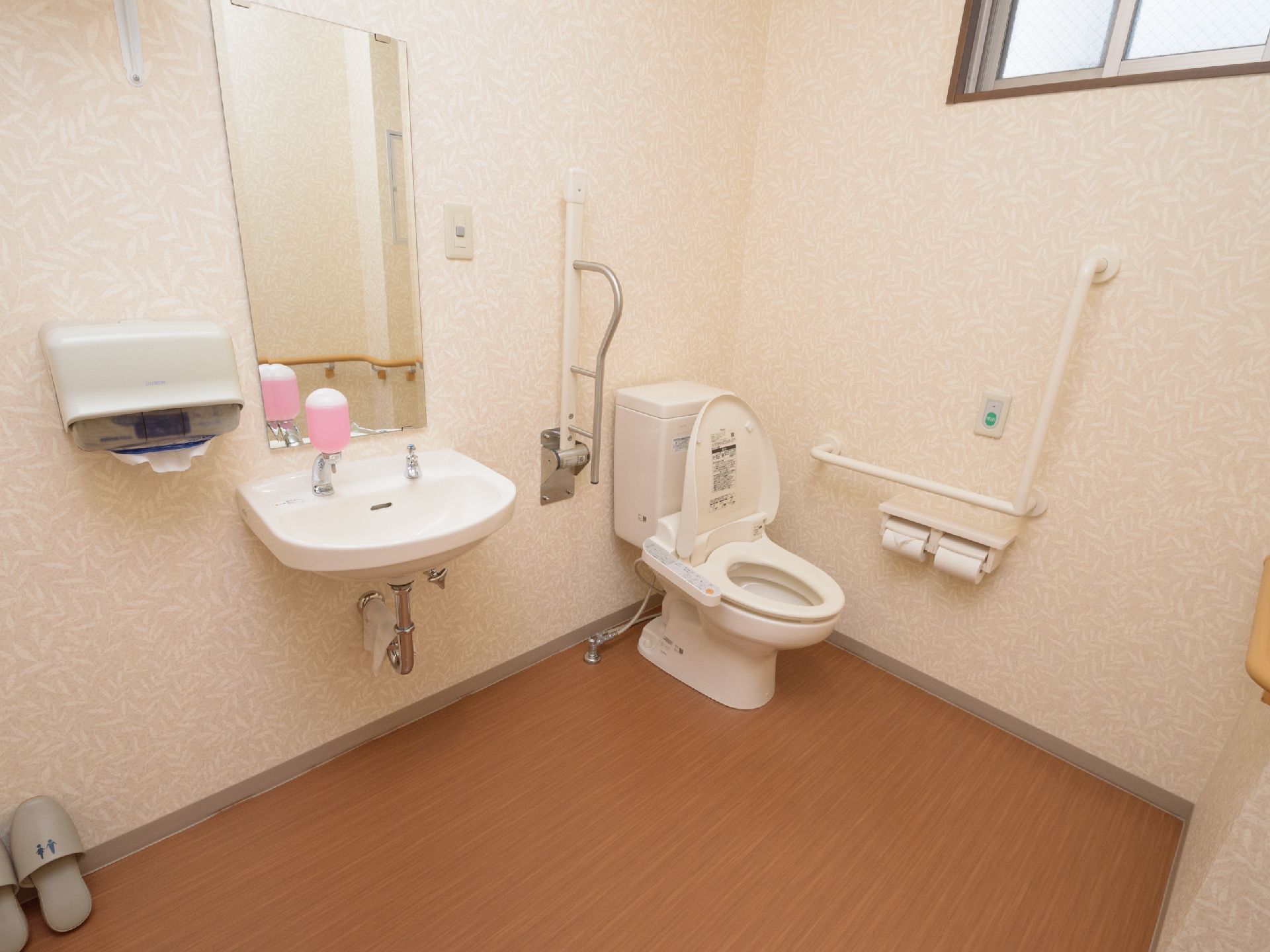 ピンク色のせっけん液が入ったボトルが設置されている、トイレ内の洗面台