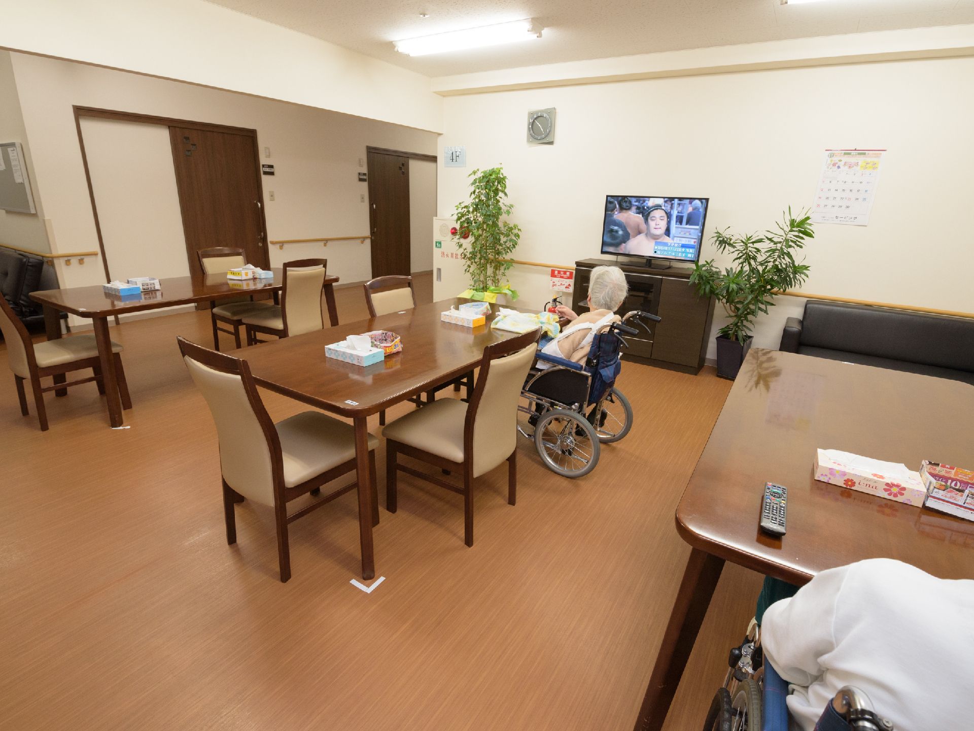壁際のテレビに近い位置にいらっしゃる、車いすをご利用の女性入居者様