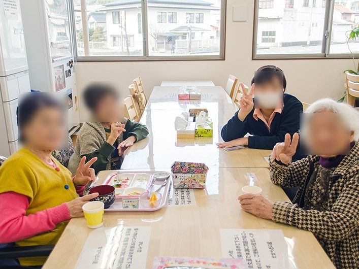 テーブルの上には施設からのお知らせが貼られており、入居者様にわかりやすいように配慮されている。窓際に観葉植物がある。