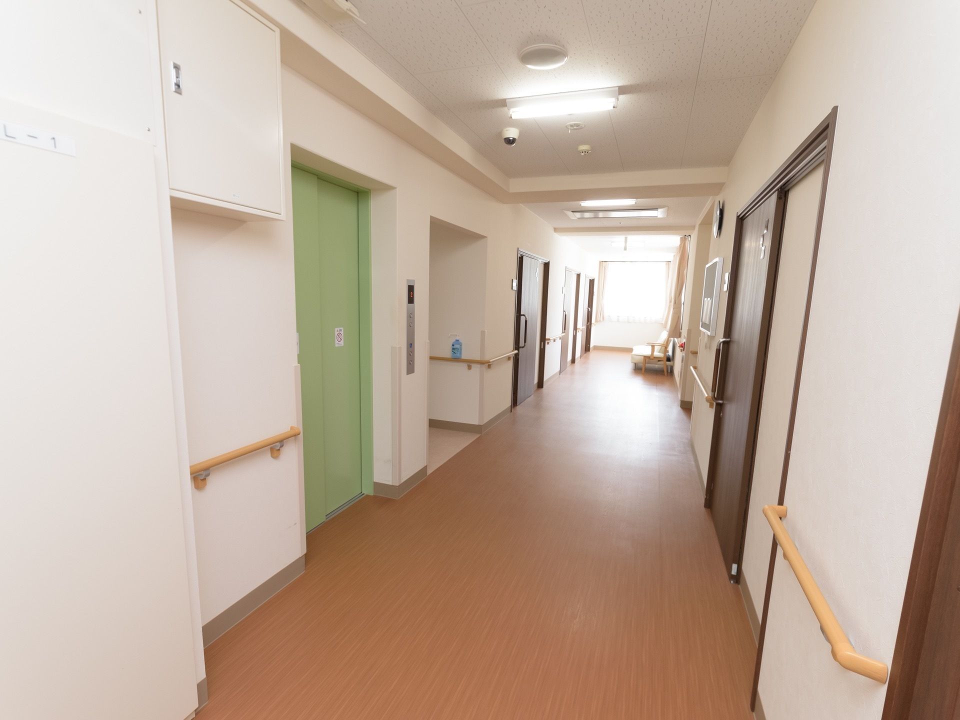 廊下の両側に手すりが備わっている。壁に凹凸はなく、まっすぐなので見通しが良い。エレベーターの扉は緑色である。