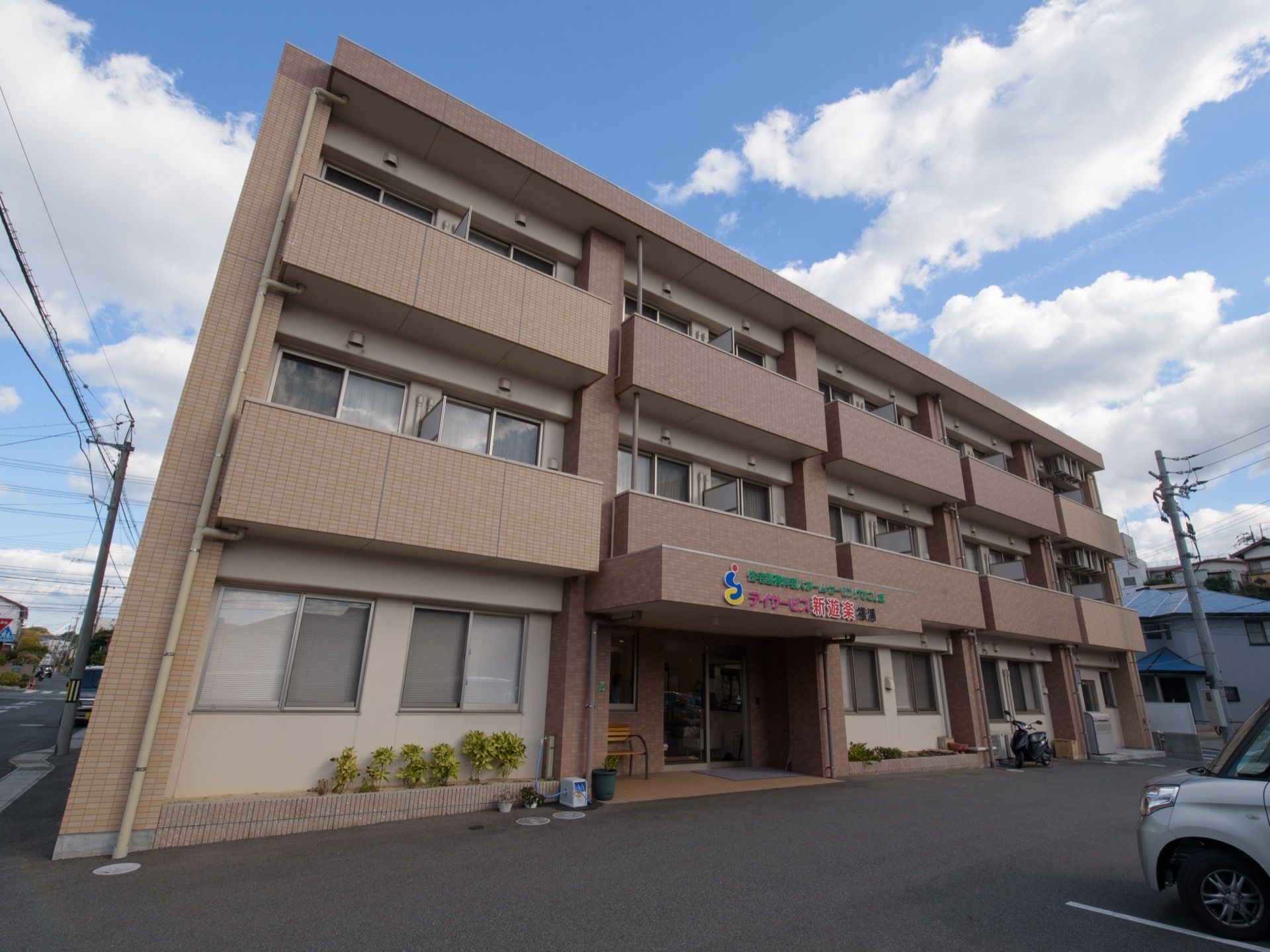 施設は３階建てで、中心に玄関があり玄関の屋根に施設名が表示されている。温かみのある色の外壁で、ごく一般的な集合住宅にも見える。