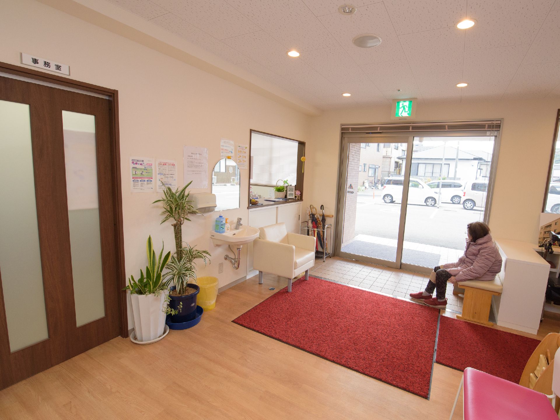 土間の壁際に置かれたベンチに腰かけている女性入居者様