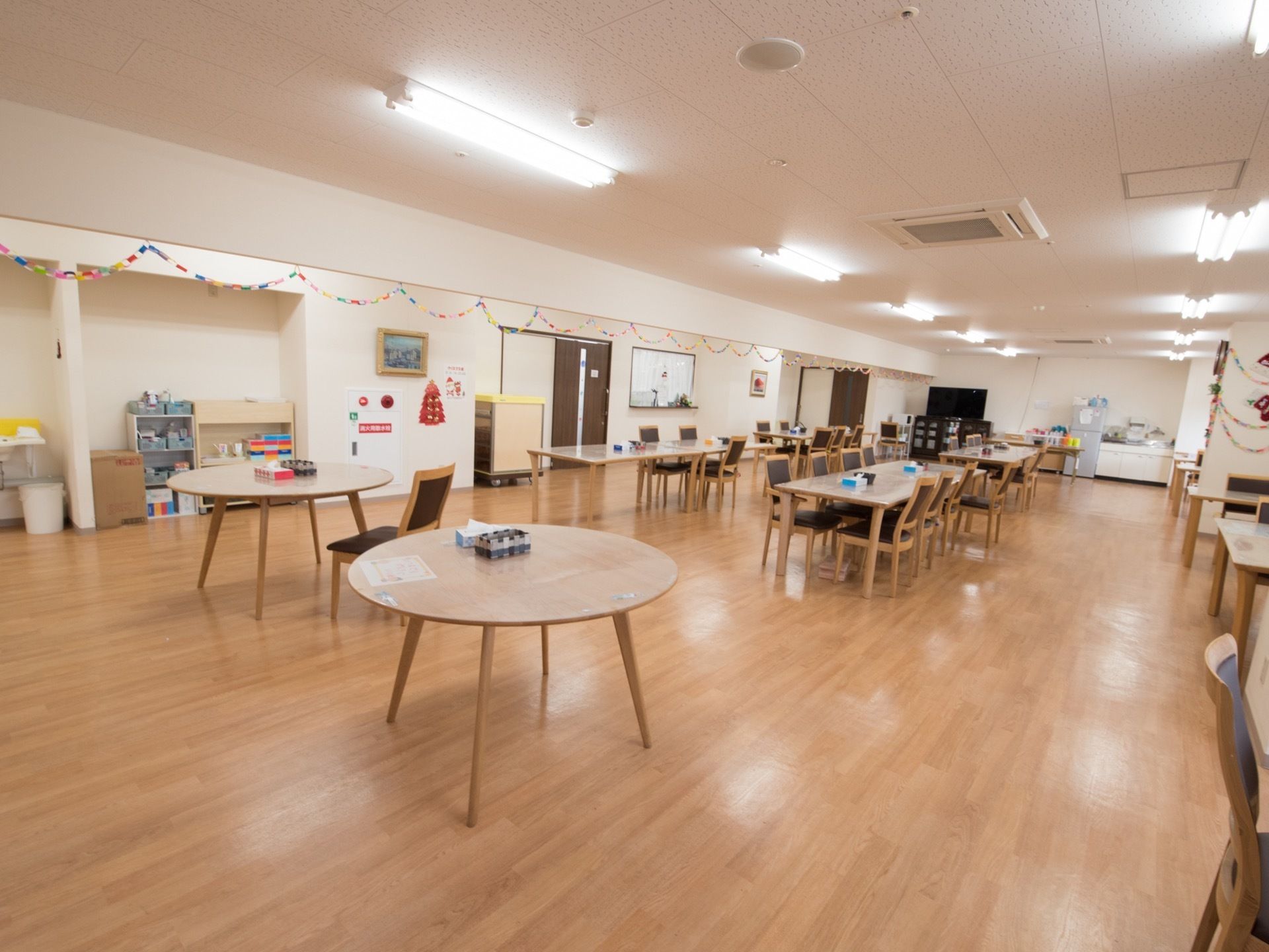 食堂の中央には入居者様用の椅子とテーブル、壁際にはキッチン、冷蔵庫、食器棚が設けられている。防火対策も万全である。