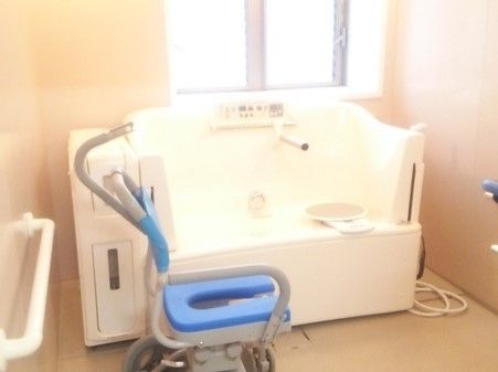 暖色系の明るく清潔な浴室には、座ったままの姿勢で入ることのできる介護用の浴槽が設置されている。窓から日光が注ぎ込んでいる。