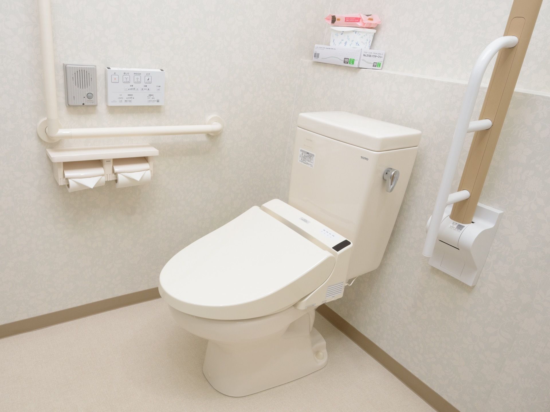 共有トイレは温水洗浄機能付きのものが使われている。左手側の肘掛けは折りたたみ式で後ろの壁に倒しておける。