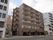 背の高いマンションのような造りをした施設建物である。１階部分に何台か入れる駐車スペースがあるのが見て取れる。