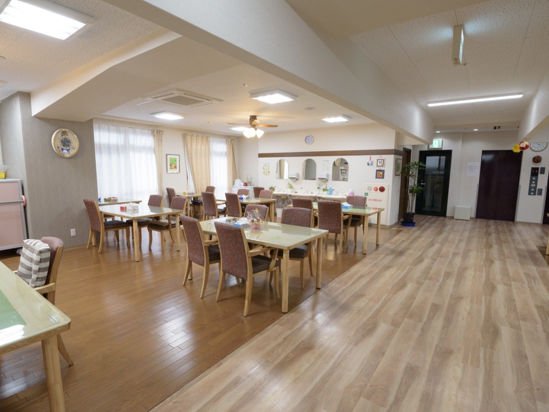 ティータイムなどの自由時間に入居者が自由に使えるリビング。フローリングの床の上に多数の座席が並べられている。