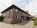 2階建ての奥行きがある建物がある。玄関アプローチはアスファルトで舗装されていて、屋根の下にはテーブルセットが置かれている。