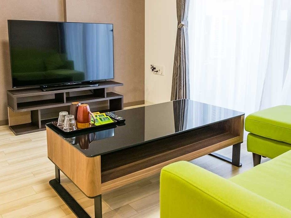 窓が大きく明るい居室には大型のテレビやソファ、テーブルなどが置かれている。