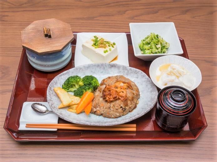 陶器の器に盛られた白いご飯と青菜のおひたし、そして肉そぼろを使ったメイン。