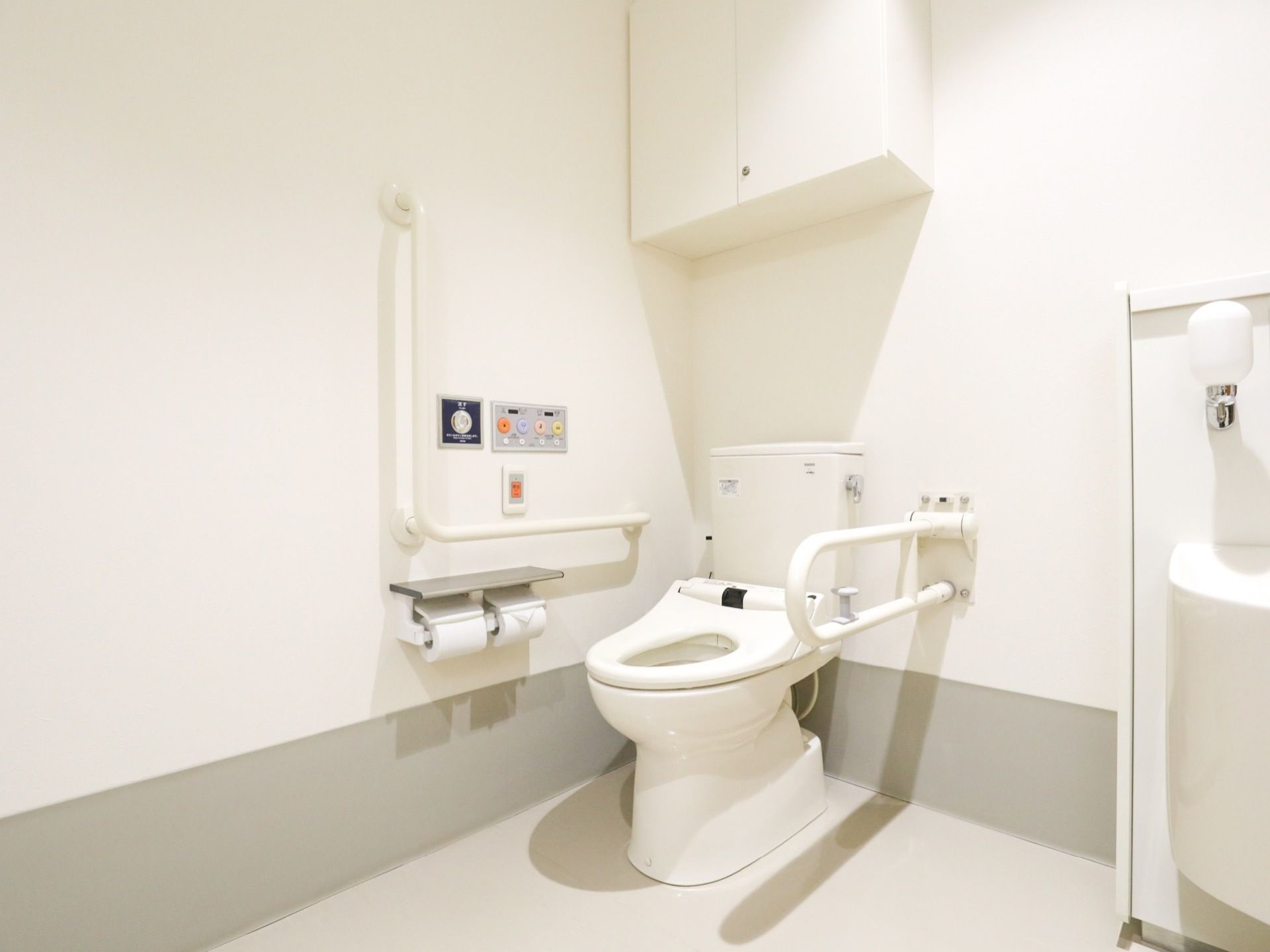 トイレスペースは広い空間を確保し、床は全面段差なく整えている。壁にはＬ字型と折り畳み式の手すりを取り付けている。