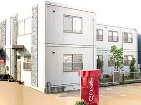 部屋の窓に柵が設置されている、白い壁の２階建ての建物