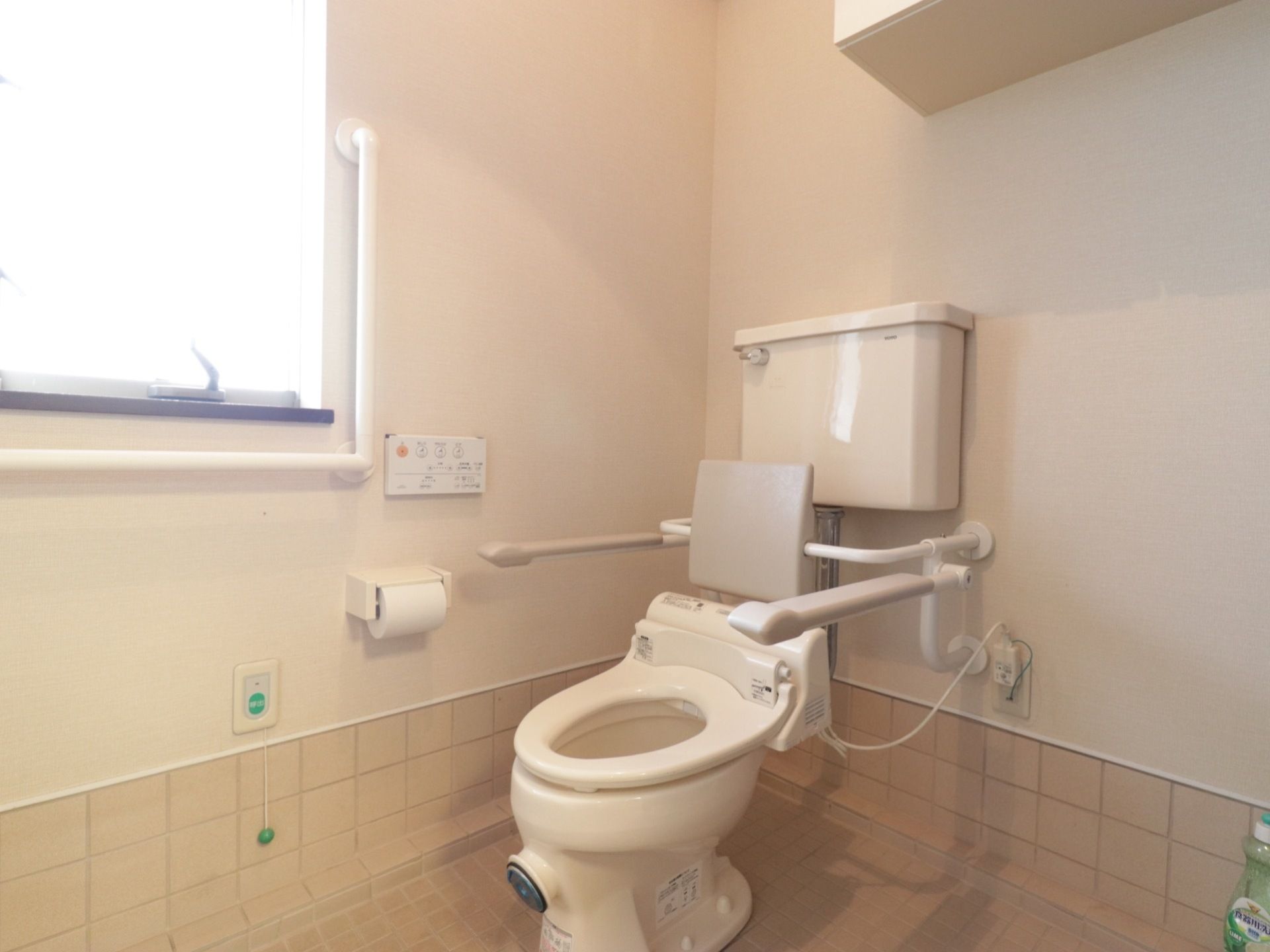 窓がある広いトイレなので明るく、体の不自由な方でも利用しやすい。肘置き、背もたれ、緊急時ボタンなど、入居者様の立場を考えている。