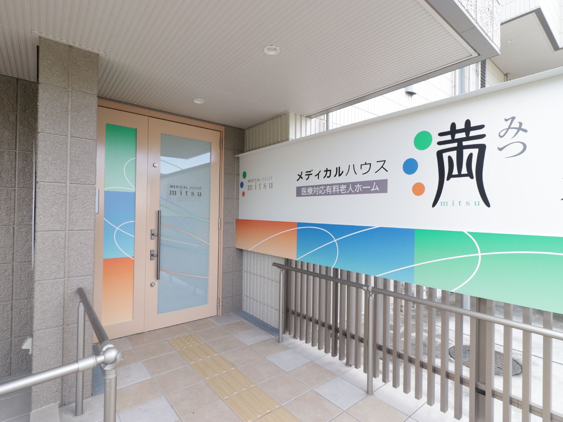玄関ドアと玄関前の壁に鮮やかな色彩で描かれている施設名