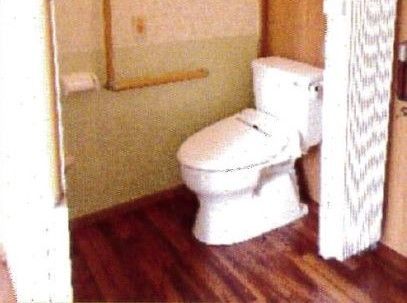 居室内のトイレ。バリアフリー設計になっていてカーテンで部屋と区切られている。手すりもついていて安心感がある。