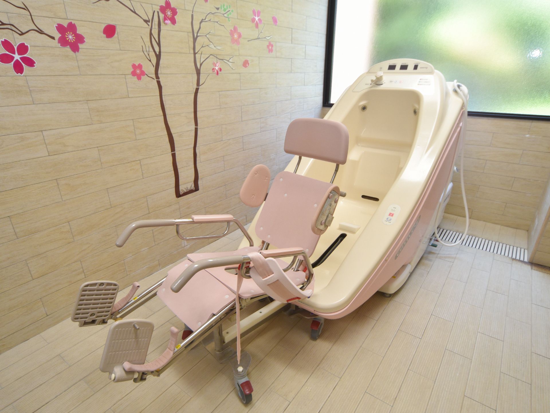 壁に桜の木を模した明るい浴室には、お身体がご不自由な方の為、ご本人には全く負担をかけない機械浴用機器を装備している。