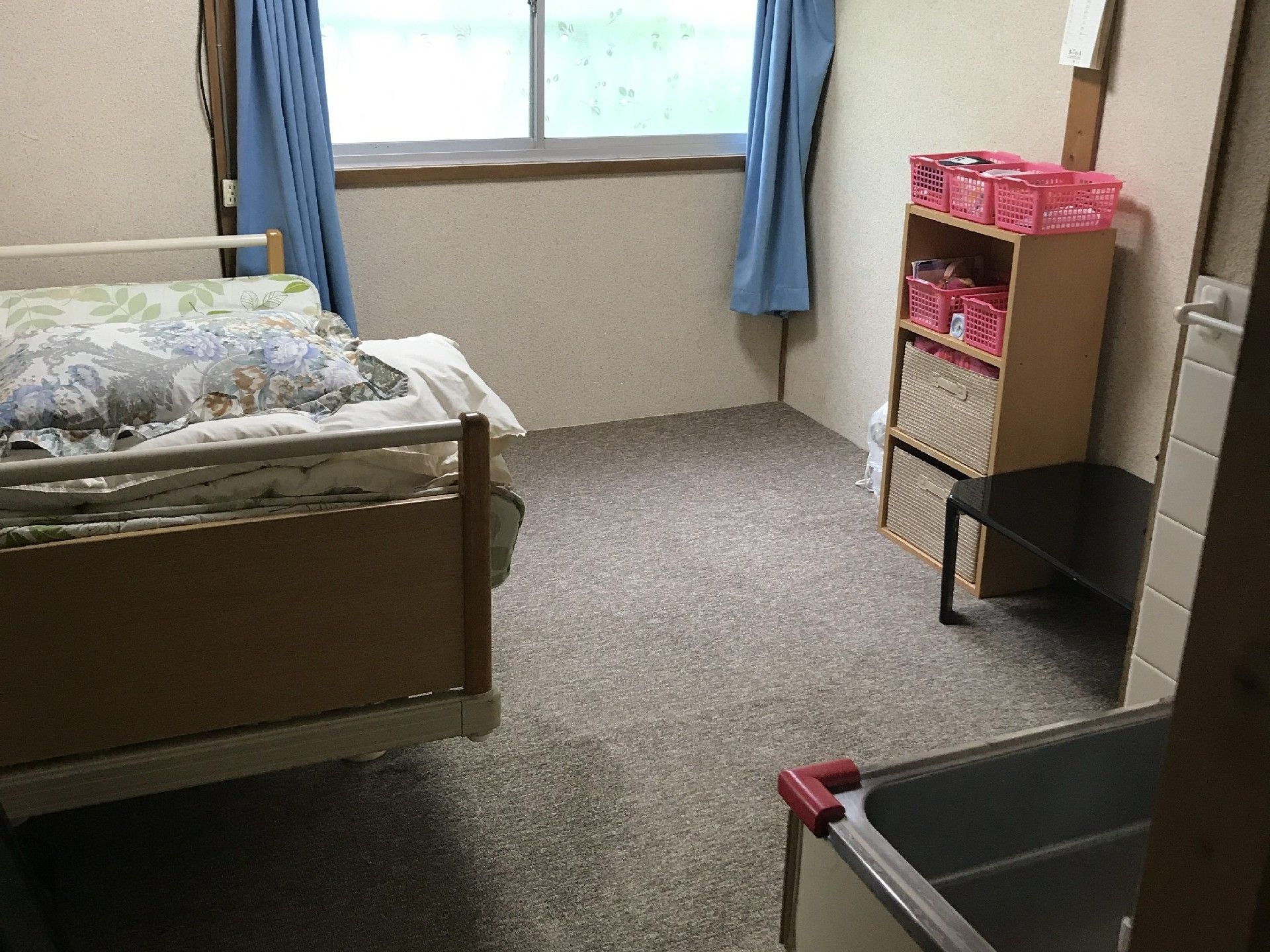 居室内には、介護用ベッドや３段ボックスが置かれている。流し台が完備されているので、洗面所を兼ねて利用できる。