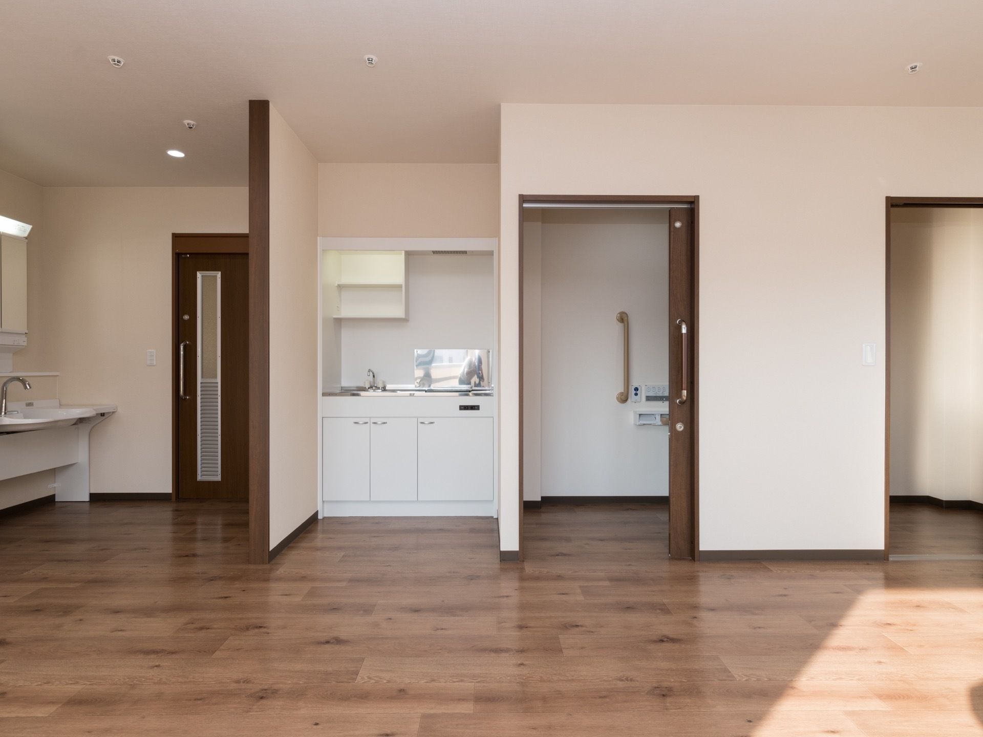 部屋に入ってすぐ右に鏡付きの洗面台がある。左に進むとキッチン、トイレが完備されている。床はフローリングになっている。