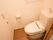 木目と白を基調としたトイレである。横側にスライド式のドアの出入口を設け、便座の正面にナースコールを設置している。