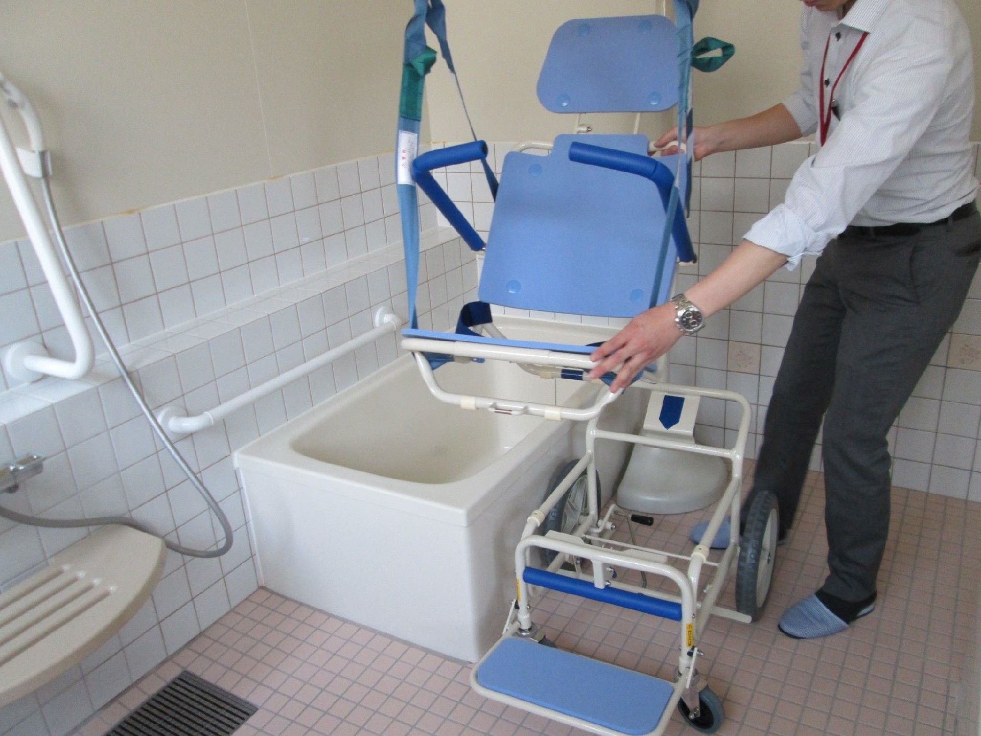 浴室内で、入浴介助用の設備について説明をするスタッフ