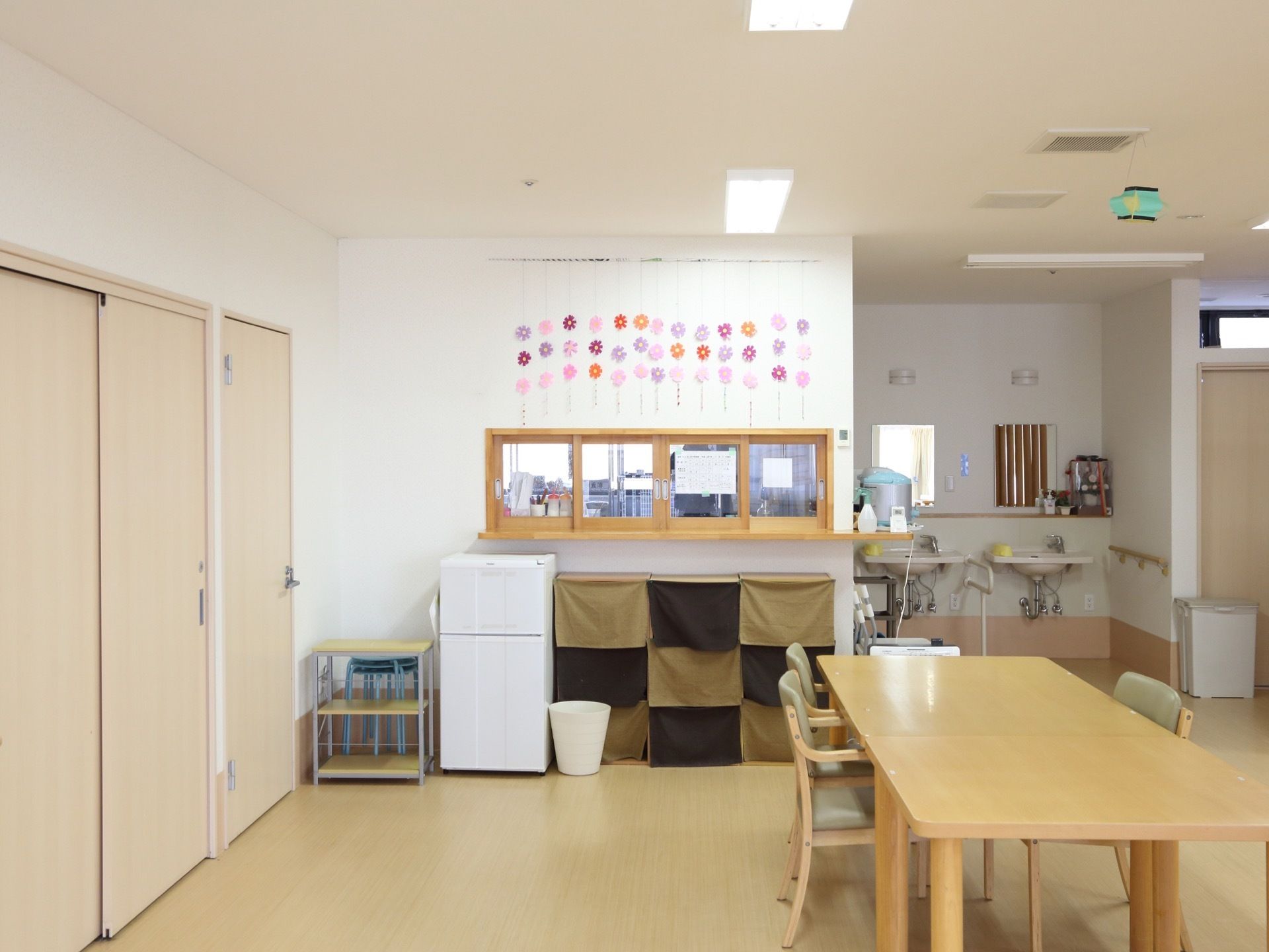奥に配膳室、洗面台、カウンター下に冷蔵庫がある。手前にはテーブルが置かれている。部屋の入り口は引き戸である。