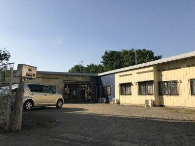 白い平屋建ての建物。入口近くに駐車場があるため、車椅子や歩行が難しい方でも利用しやすい構造となっている。