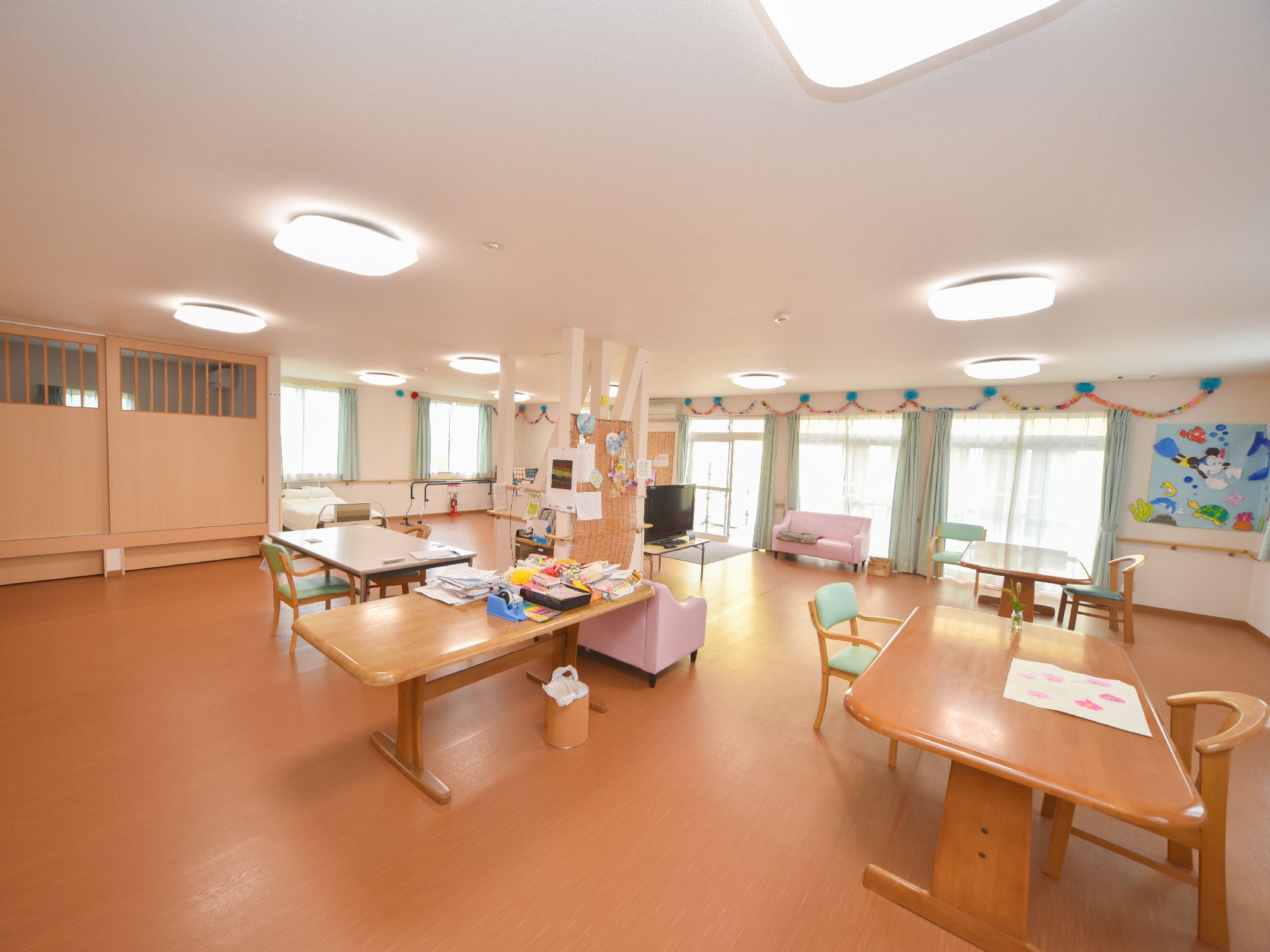 部屋には大きな窓があり、昼間には明るい陽射しが入る。壁には折り紙で作った輪っかの飾りや大きな絵が飾られている。