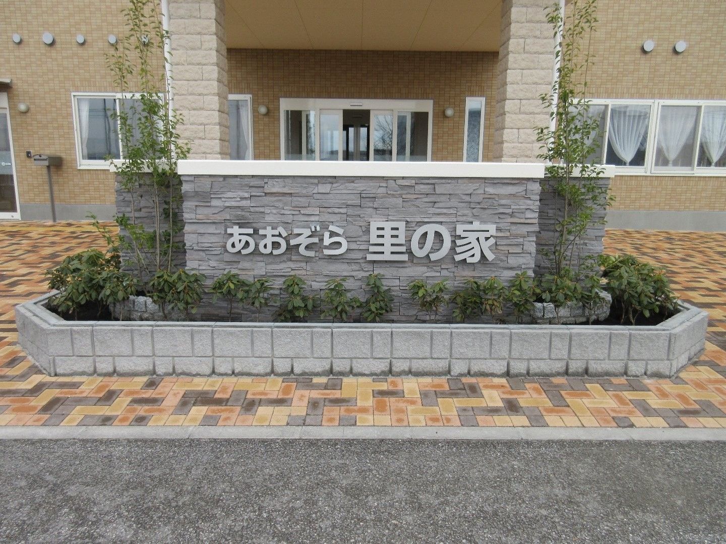 レンガの柱や床などがおしゃれで温かみのある外観。グレーのレンガに、同系色で施設名が取り付けられている。