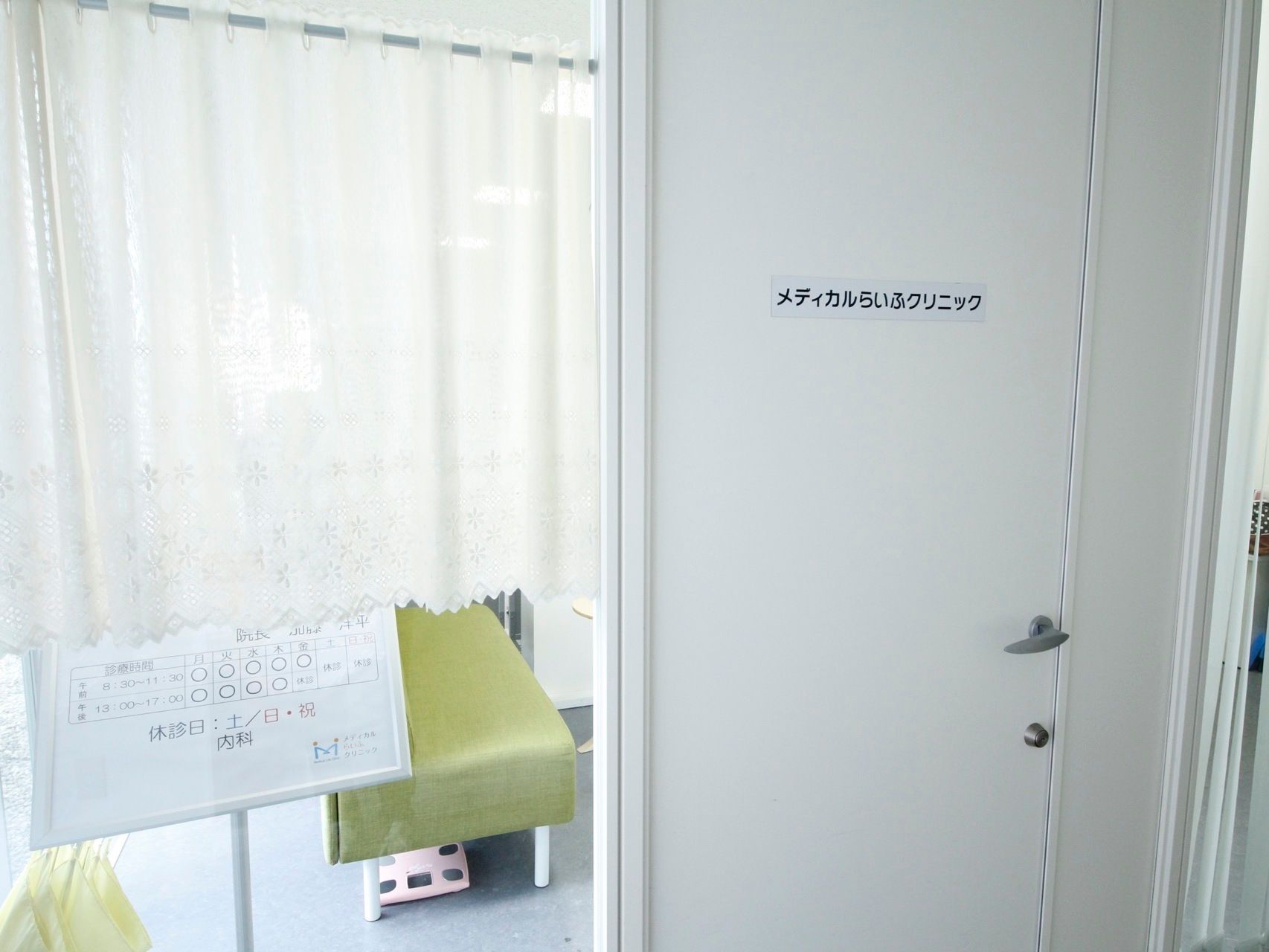 クリニックが敷地内にあり、清潔感のある建物である。扉は白く、窓にはレースのカーテンが掛けられている。