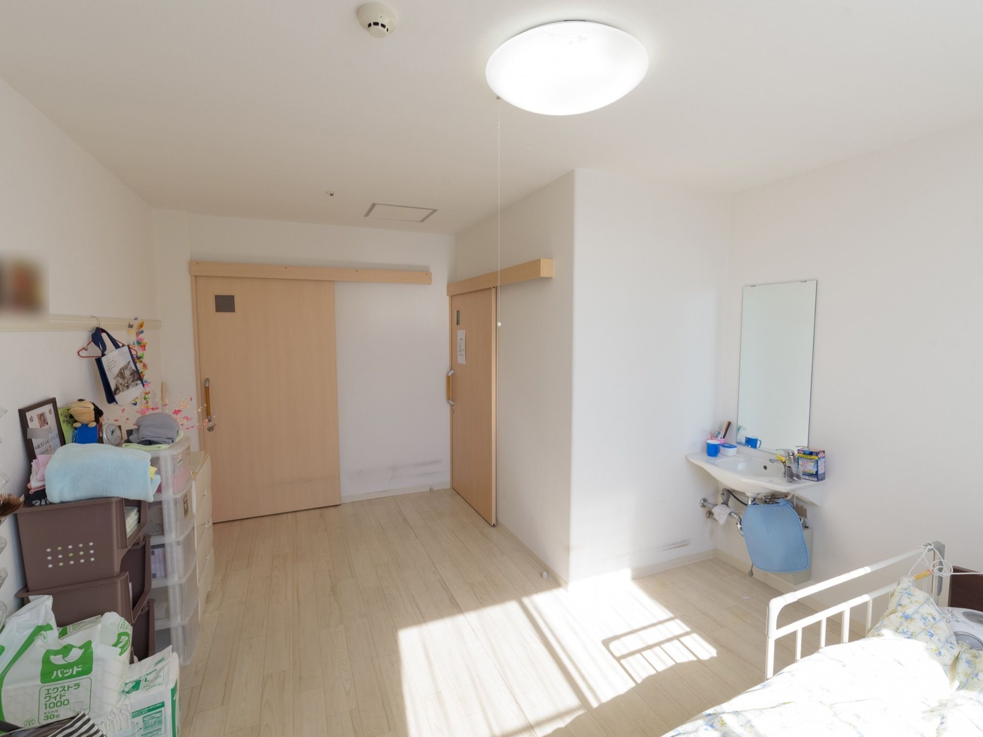 白が基調の優しさを感じる明るい居室は家具を置いても広さが十分ある。介護用ベッドのそばに洗面スペースがあるので便利である。