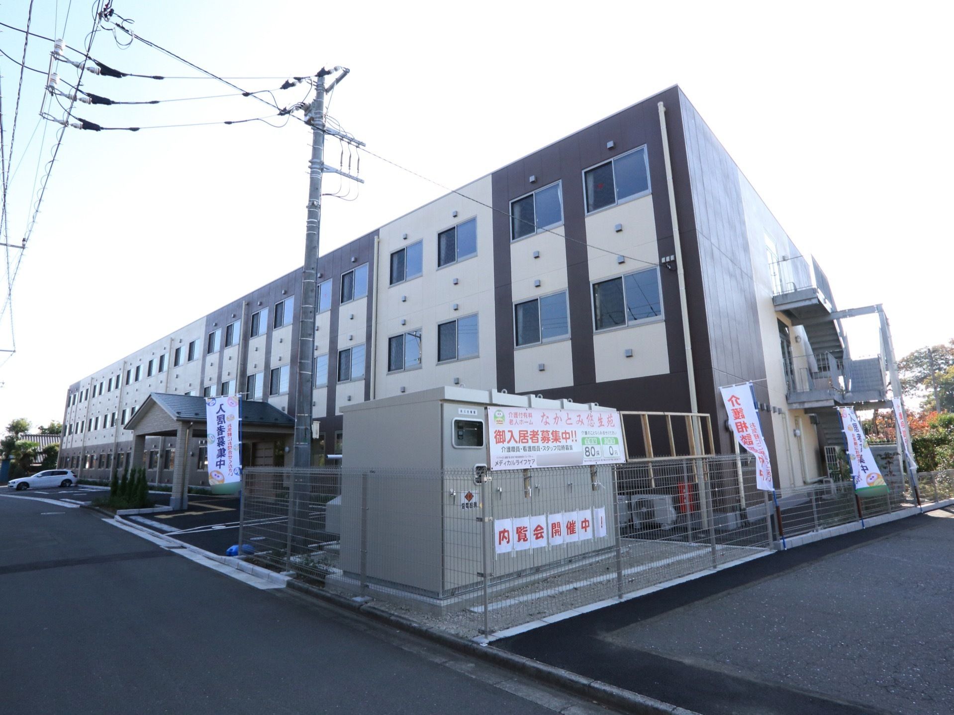 施設はブラウン系の横に長い建物である。外周にはワイヤー製のフェンスを設置し、様々なのぼりなどを掲げている。
