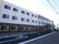 施設の建物は三階建てで、玄関前には大きな屋根を設置している。前面にはアスファルト舗装の駐車場を設けている。