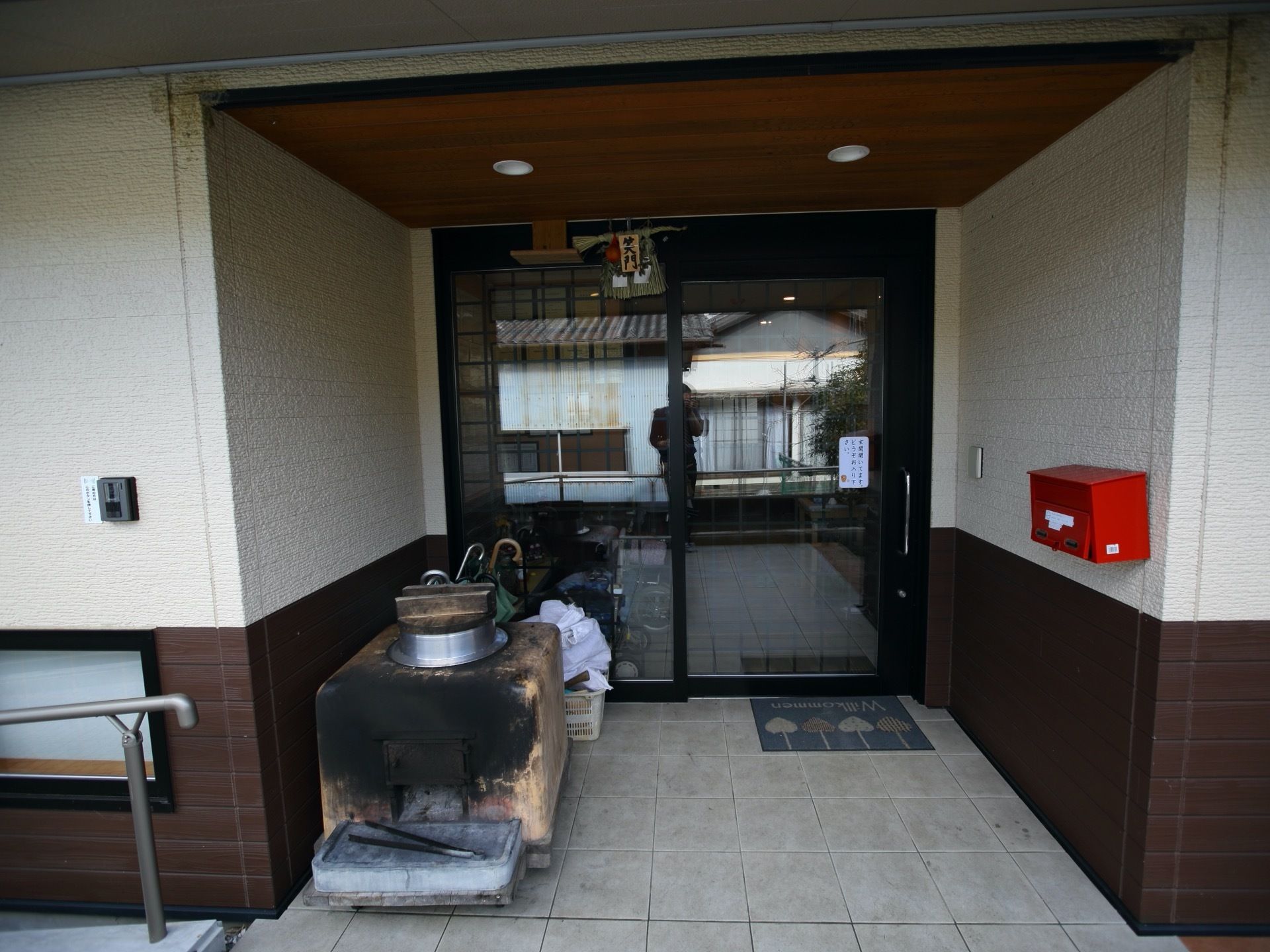 施設の入口はガラスのドアで、中の様子がよく分かるようになっている。郵便物を入れる赤いポストや来客用のインターフォンがある。