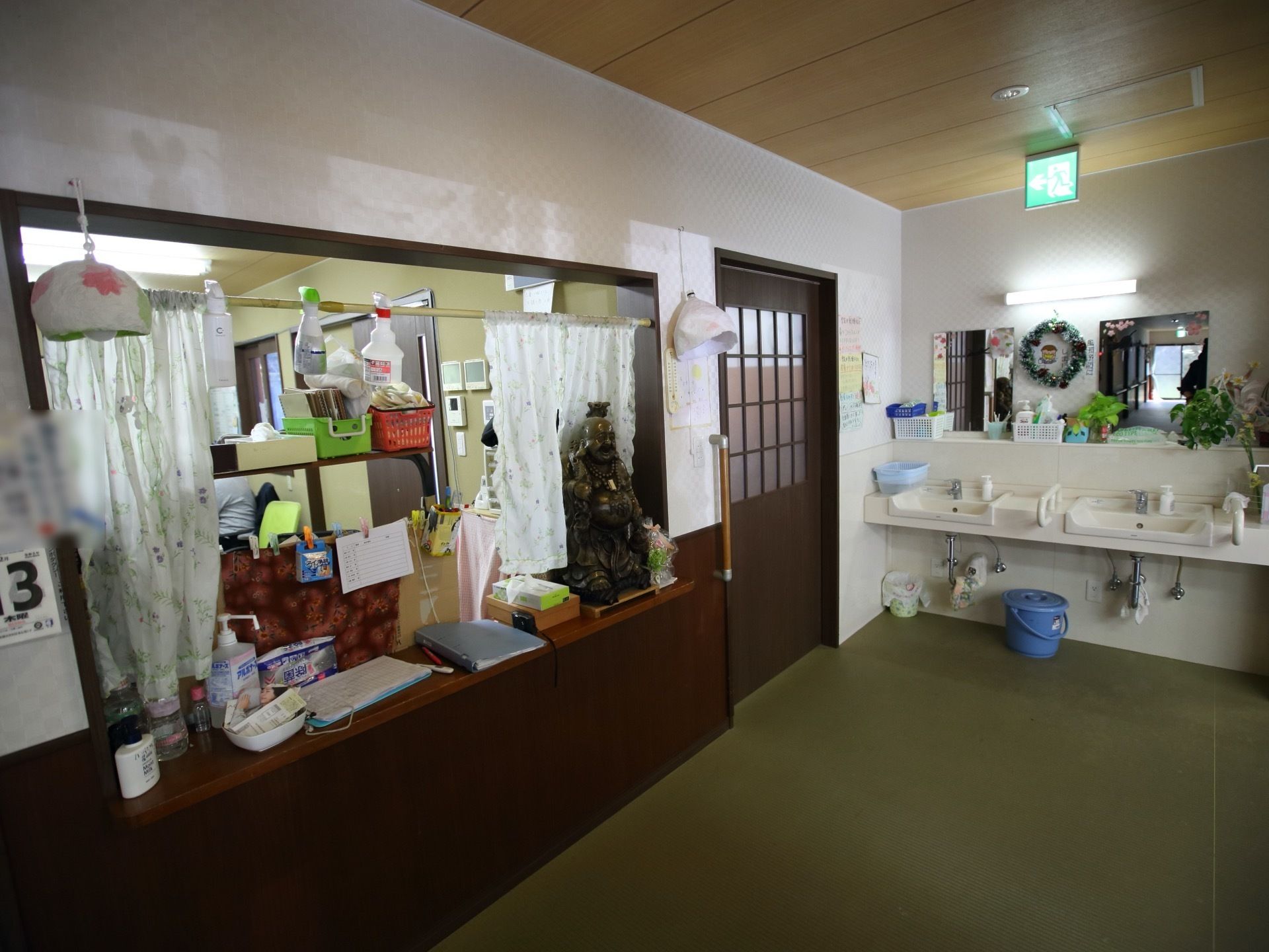 洗面台が２つ並んで設置されている。洗面ボウルの横に手すりがついているタイプである。事務室に通じるカウンターには小物が並べてある。