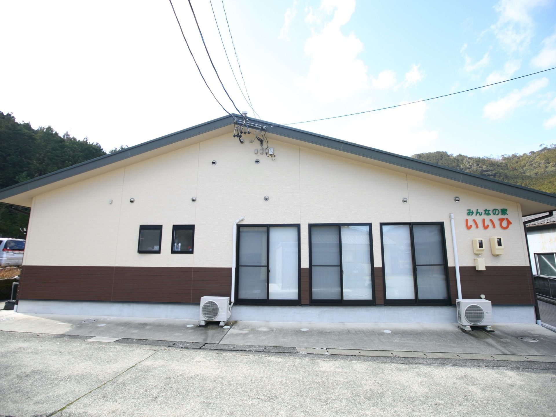 施設は白色の平屋建てで三角屋根がついている。施設の前には車道があり、車で通る際には壁に表示された施設名を確認することができる。