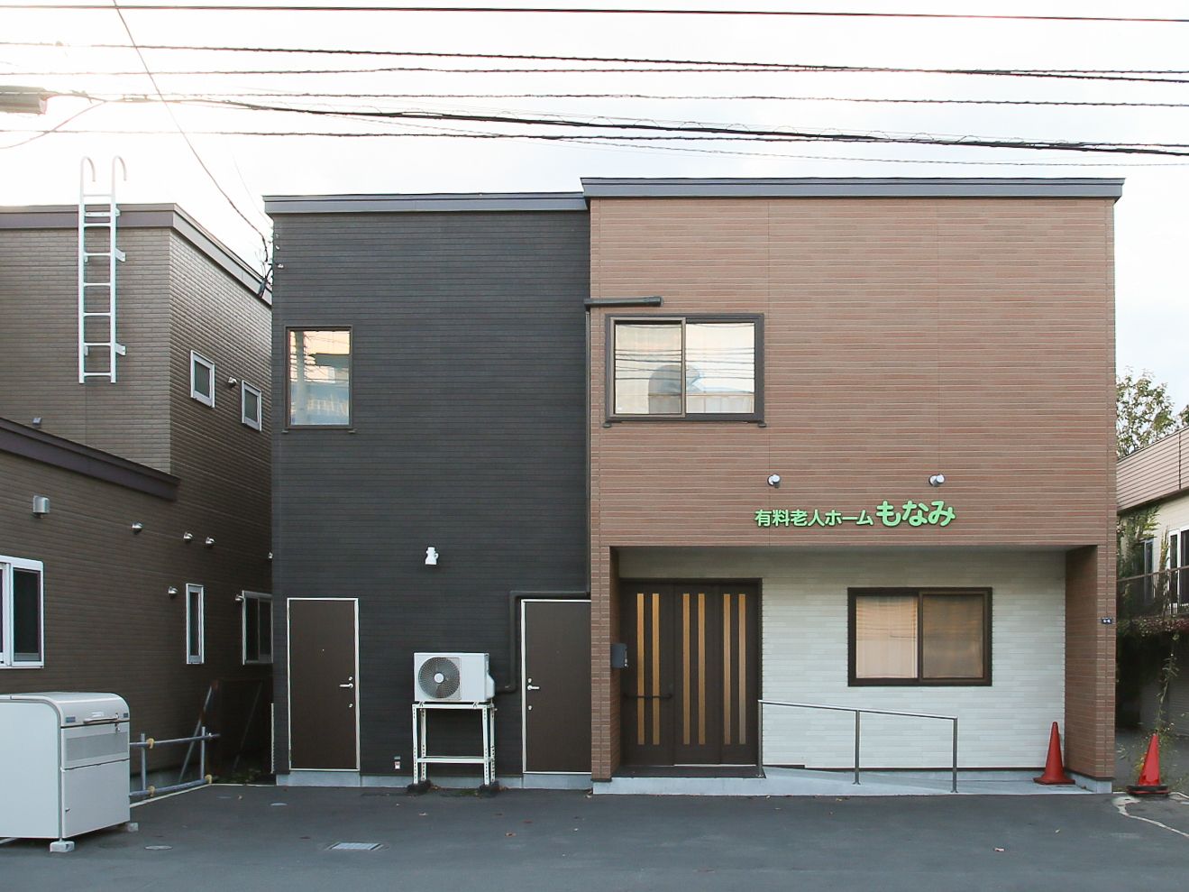 ダークブラウンを基調とした２階建ての外観は、落ち着いた雰囲気である。玄関上の側面に白文字で施設名を表示している。