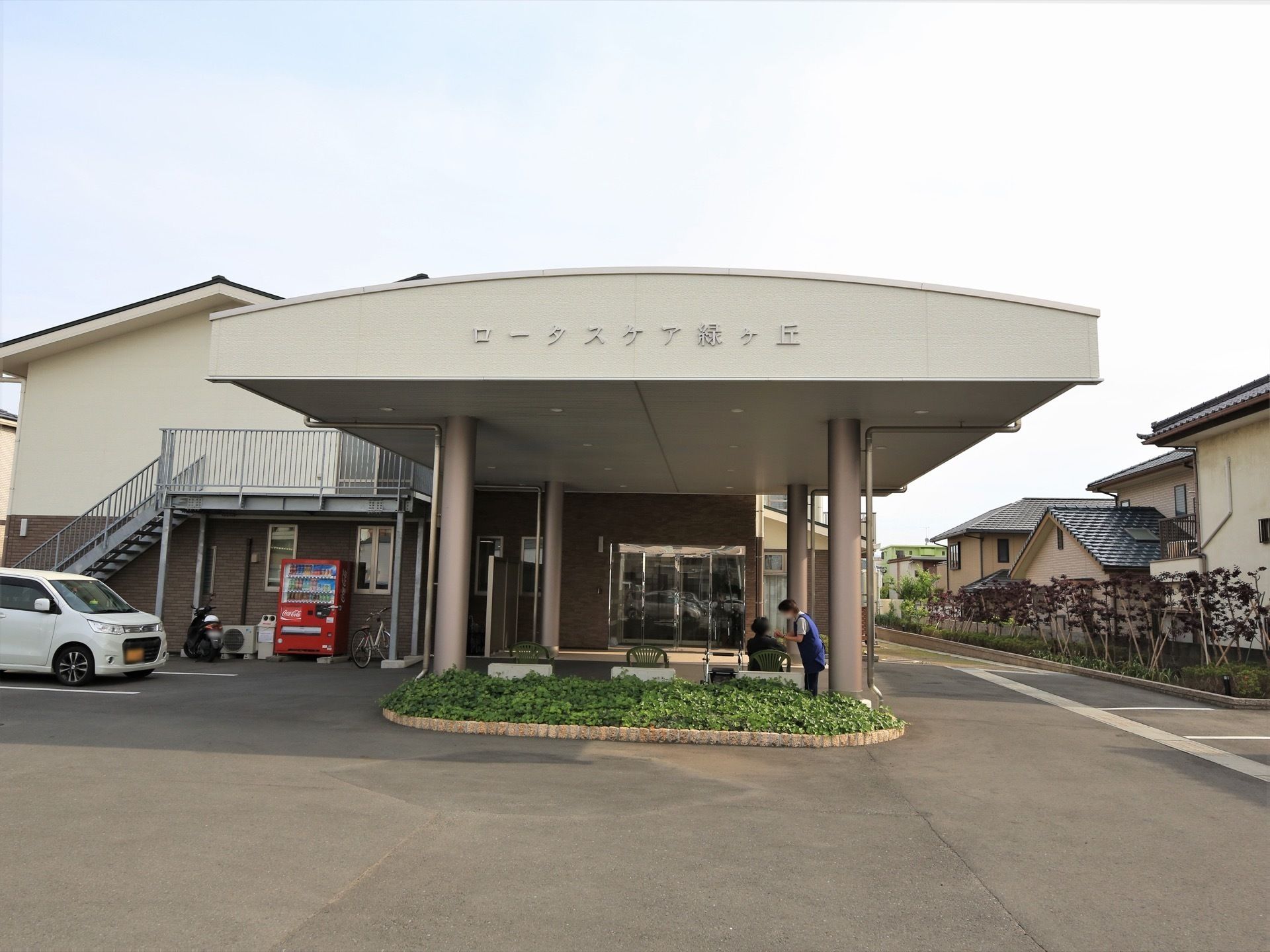 エントランスには大きめのタイルを配置している。ドア前の屋根はラウンド状で、前面に施設名を明記している。