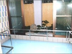 広い浴槽のある大浴場。ブルーを基調としたデザイン性のある壁である。大きな窓からは、日本庭園のような景色が楽しめる。