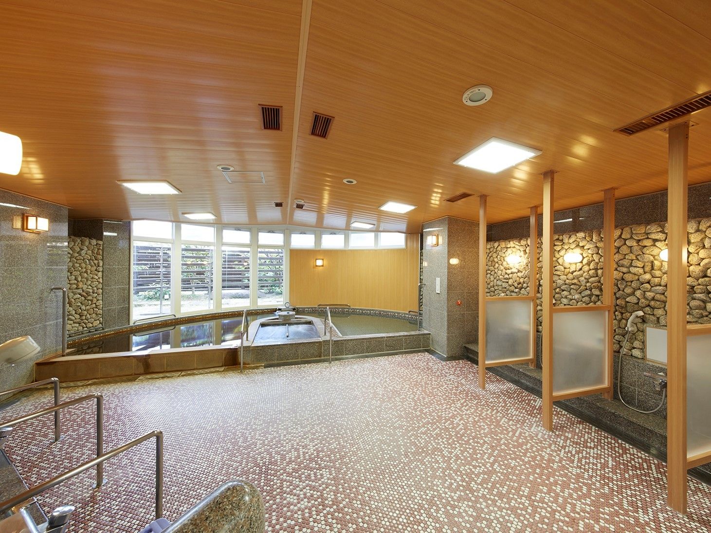 モザイクタイル張りの床に石積みの壁が、観光地の温泉のような雰囲気を感じさせる。広い浴槽には、おごと温泉の源泉を用いた湯が張られている。