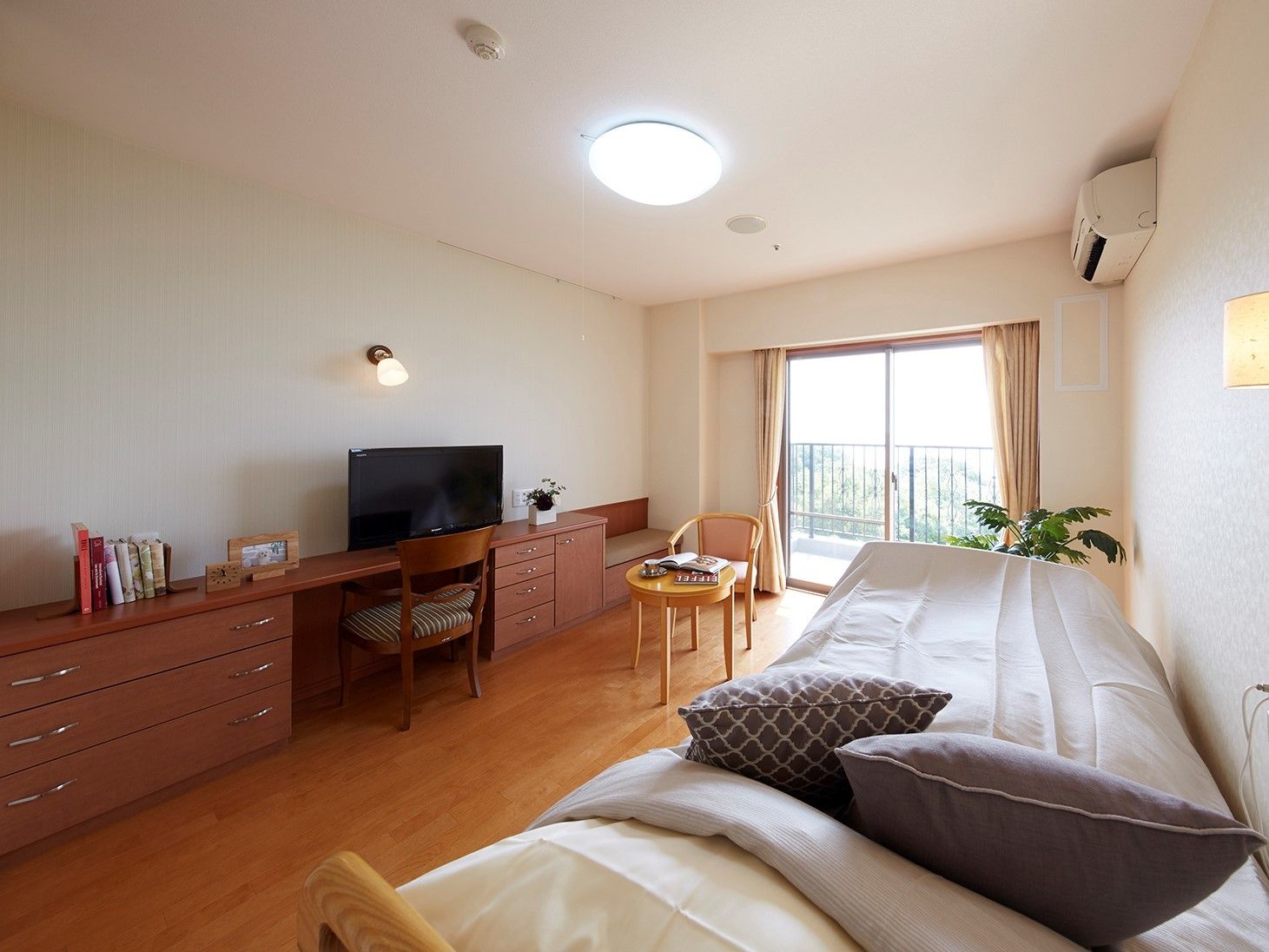 壁に沿って、木製のデスクとサイドボードが設置されている。テレビ台も兼ねており、大型テレビが置かれている。