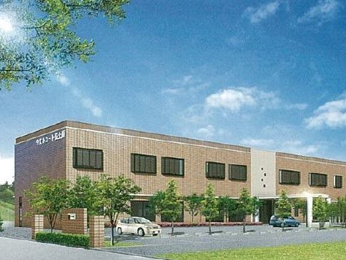樹木の植えられた広い駐車スペースがある、横長でレンガ調の建物
