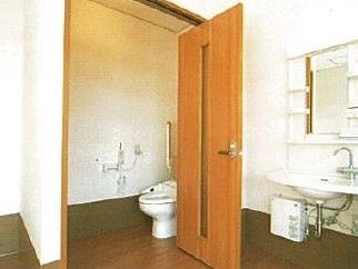 便器には温水洗浄便座が付いている。便器横の壁にはナースコールが設置されている。トイレの外にある洗面台は下がオープンになっている。