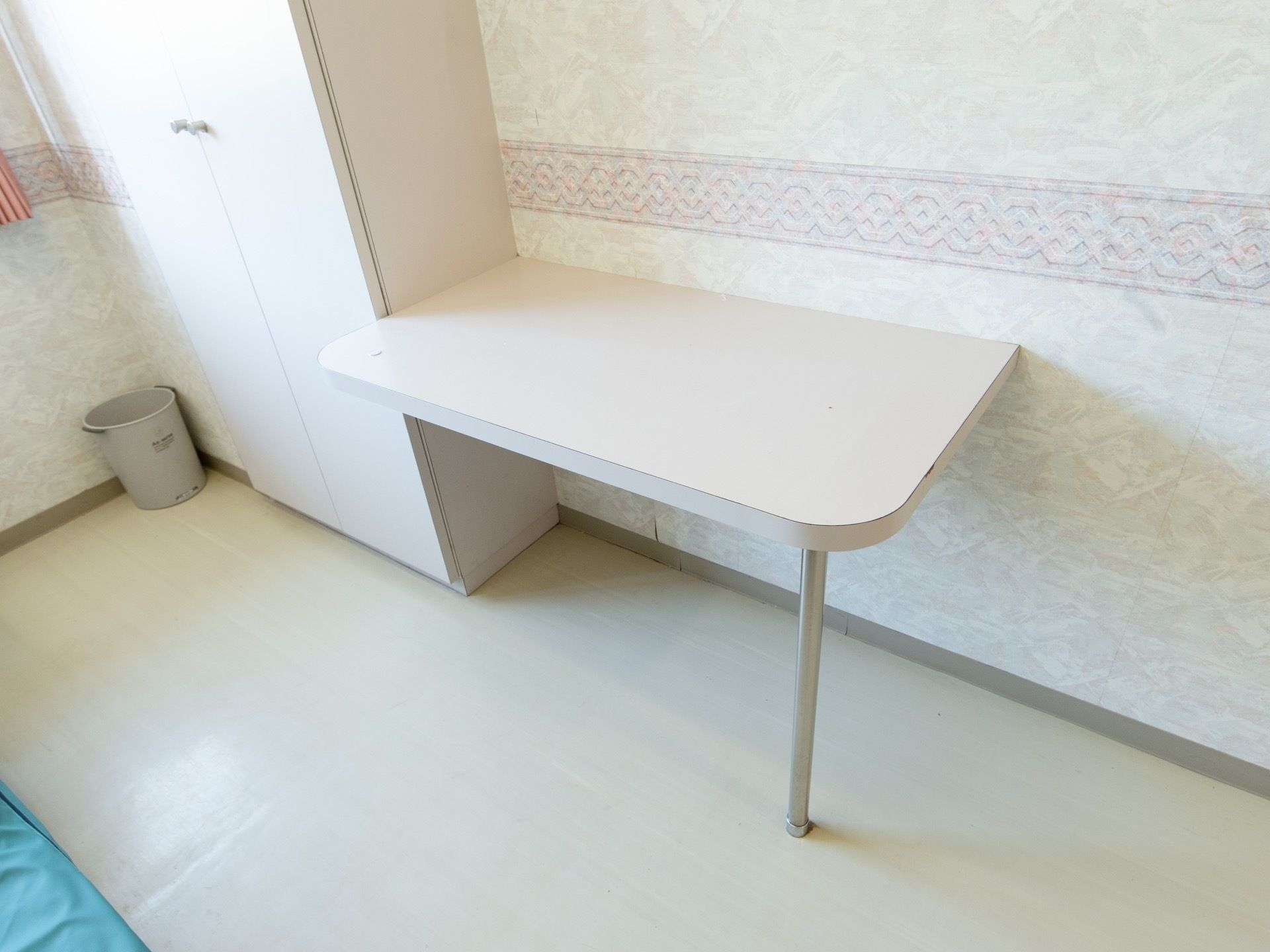 クローゼットと壁に面してテーブルが備え付けられている。白色を基調とした内装で、清潔感のある雰囲気である。