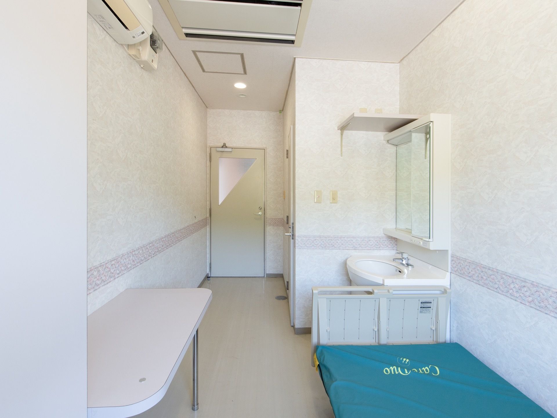 白色を基調とした明るい雰囲気の内装で、介護用ベッド、洗面台、エアコンなどが備え付けられている個室である。