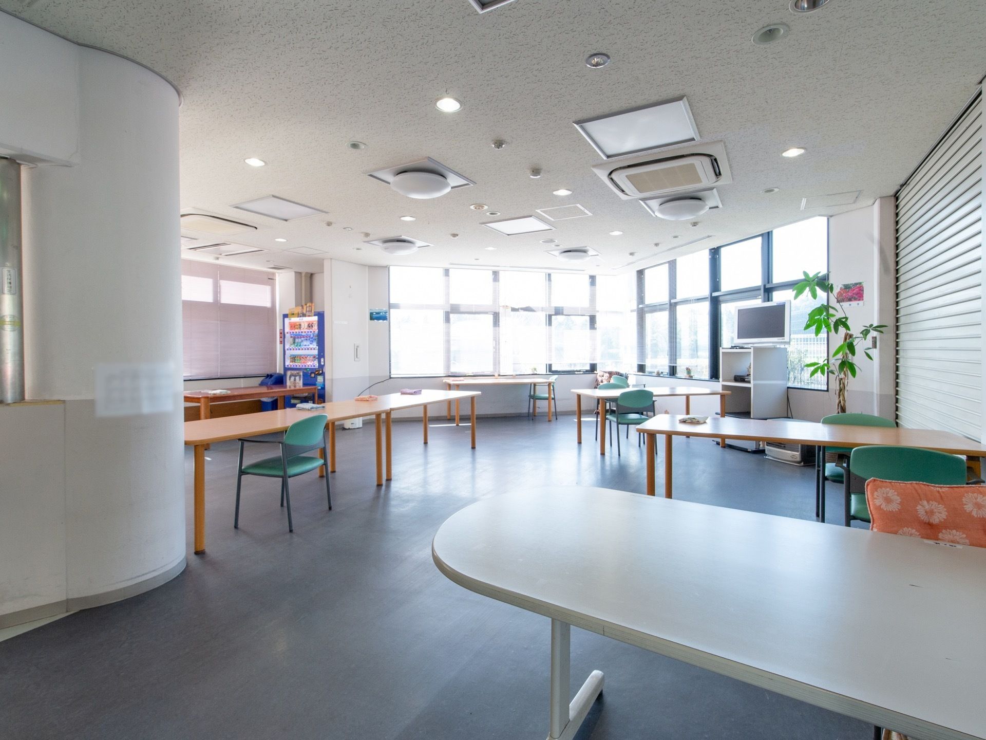 広々としたスペースに、テーブルや椅子が並べられ、壁際には飲料の自動販売機が置かれている。窓が多く、明るい雰囲気である。