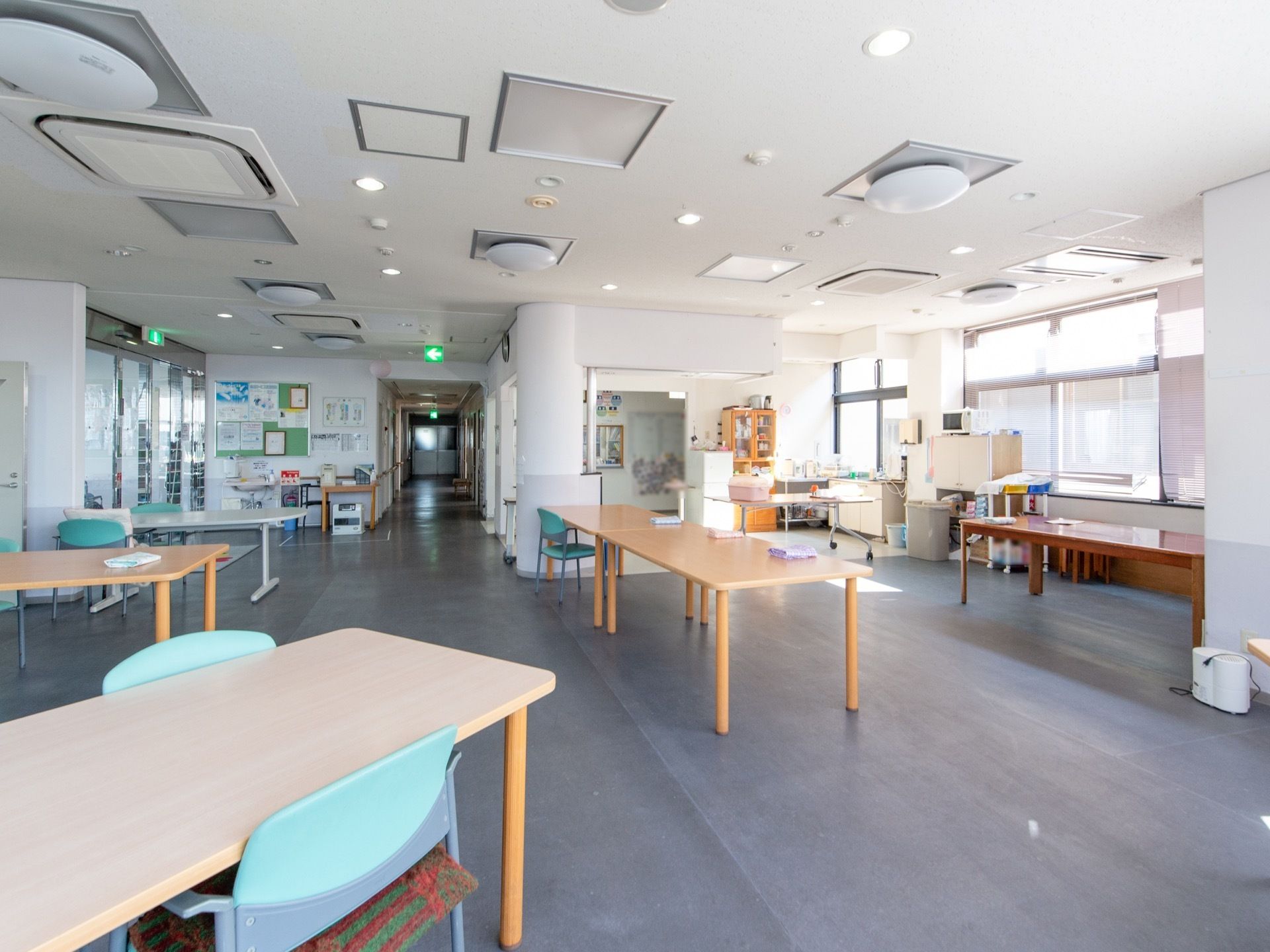 広々とした部屋に数台のテーブルと数脚の椅子がランダムに置いてある。天井にたくさんのシーリングライトとダウンライトが設置されている。
