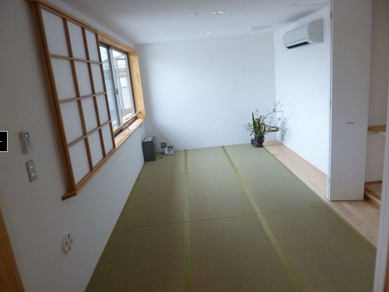 畳が敷かれた和室である。腰高窓には手すりがあり、手前には障子が入っている。エアコンと電話が付いている。