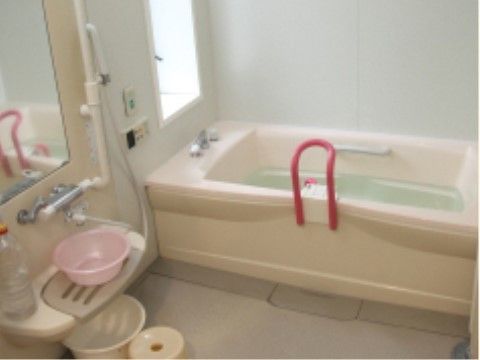 浴槽の近くには手すりがあり、緊急呼出ボタンも設置され安全性が確保されている。壁には採光に優れた窓があり、鏡、シャワー台が設置されている。