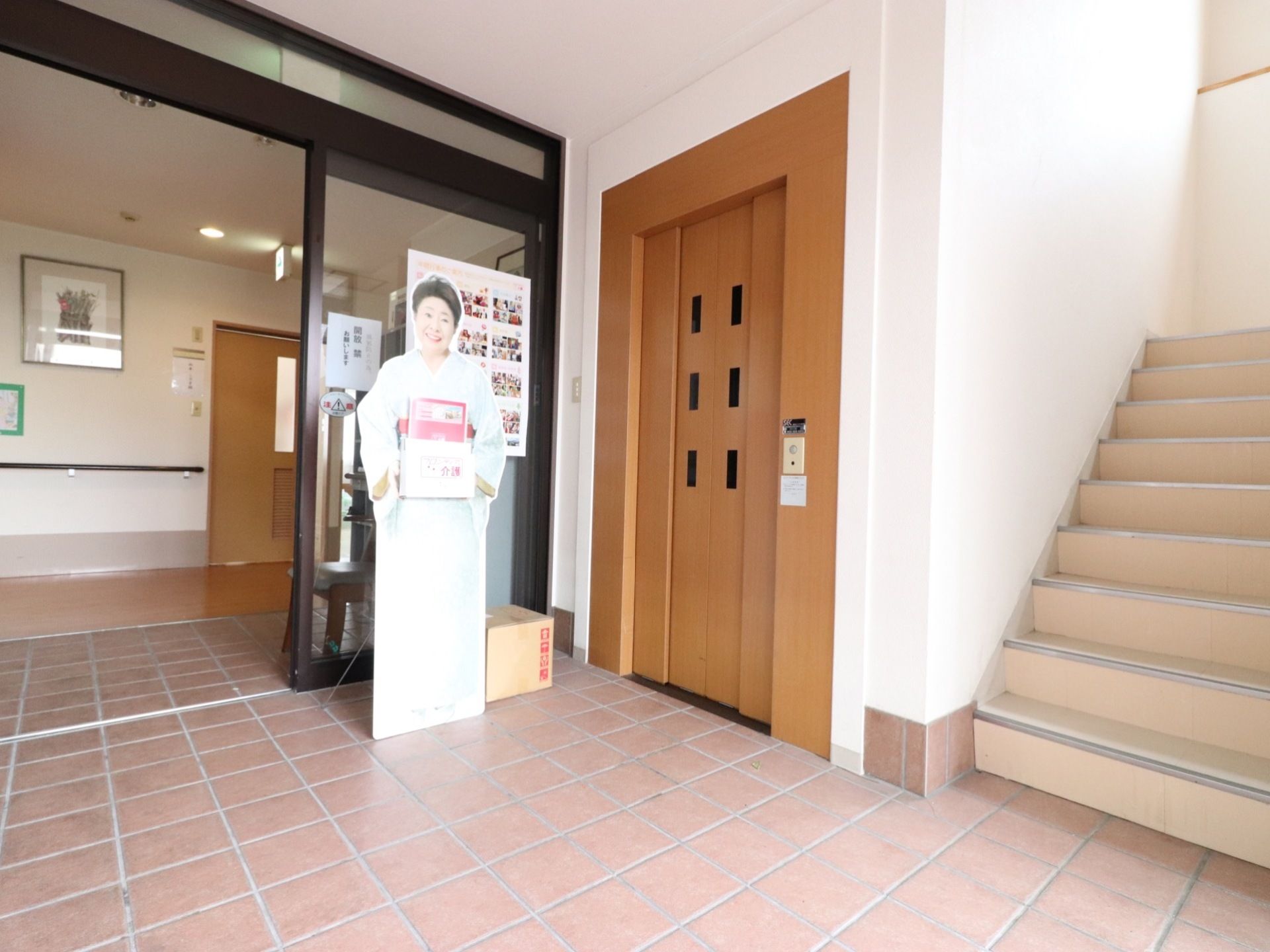 階段とエレベーターが隣り合っており、通路は淡い茶色のレンガ張りの床面になっている。明るく通路幅が広いので開放的である。