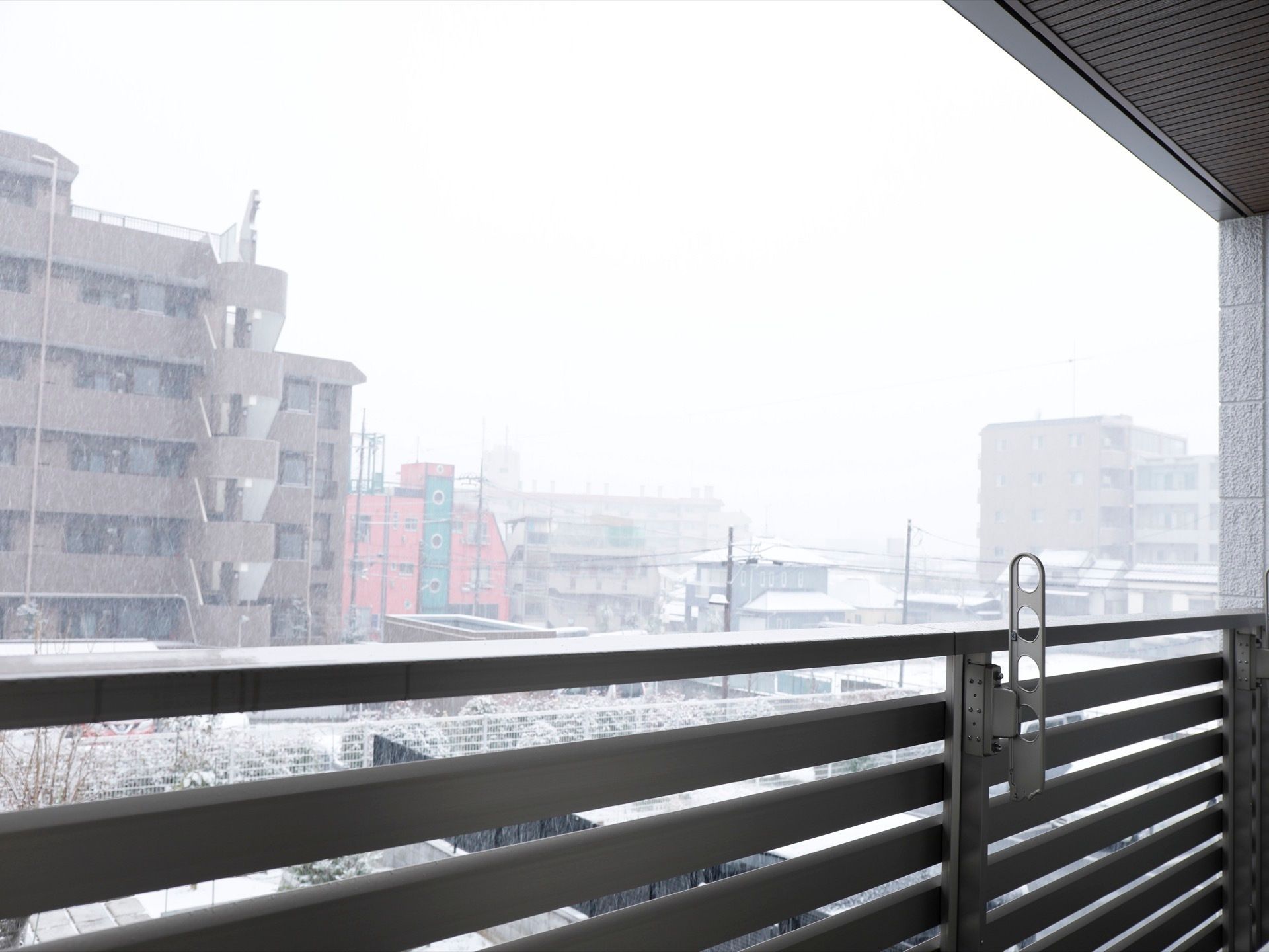 ベランダには物干しを利用できるようにフックが設置されている。都市中心部の景観で雪が降り積もる季節である。